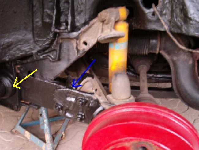 Hinterachse des Doppelgelenk-Fahrgestells: Der blaue Pfeil weist auf die Zone hin, wo starke Anrostungen zwischen den verschraubten Teilen auftreten knnen!